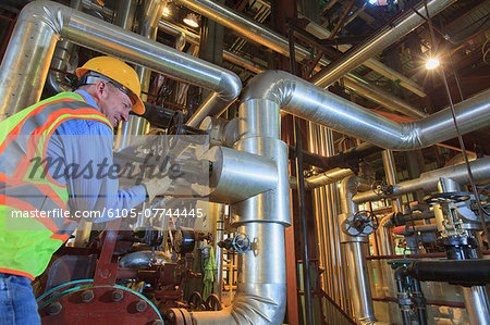 Engineer in electric power plant adjusting condenser piping valve