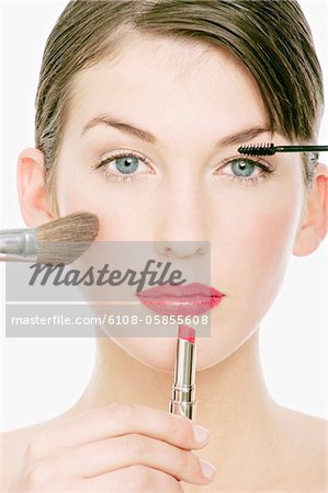 Young Woman face with Make-Up, a pencil, lipstick and a brush in front of her, close-up (studio)