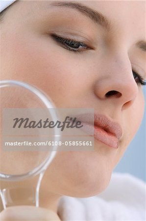 Young Woman with a magnifying glass, close-up (studio)