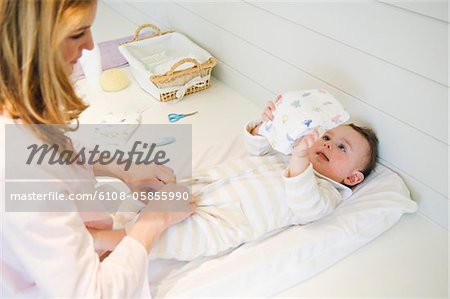 Woman undressing her baby lying