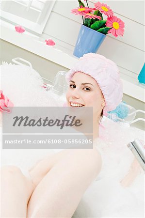 Young woman having a bath, smiling for the camera