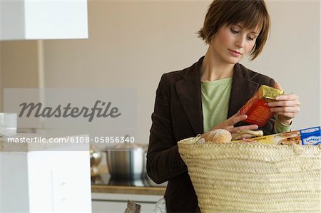 Young woman emptying shopping basket in the kitchen