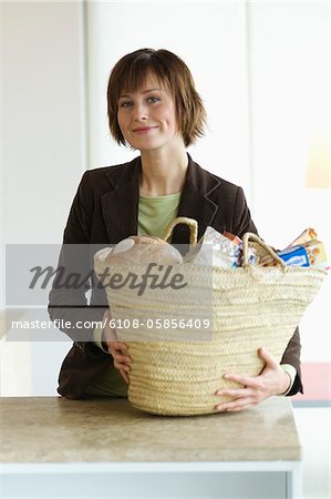 Young smiling woman with shopping basket in the kitchen