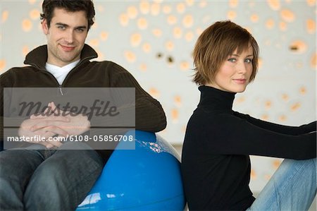 Couple sitting in living-room, looking at the camera