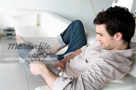 Man lying on a sofa, reading magazine