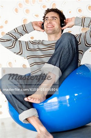 Smiling man wearing headphones, sitting in a blue armchair