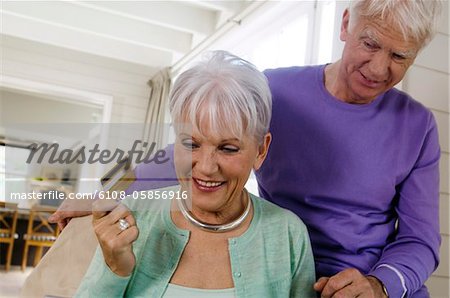 Senior couple inthe living-room, woman holding credit card