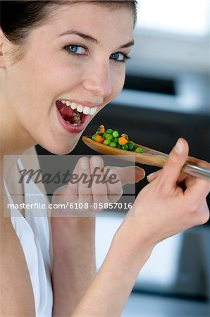 Young smiling woman tasting cooked vegetables