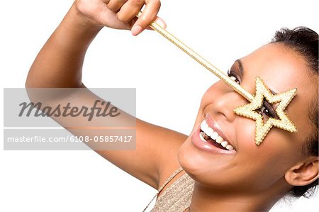 Portrait of a young smiling woman looking through magic wand