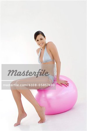 Young smiling woman, sitting on big pink balloon