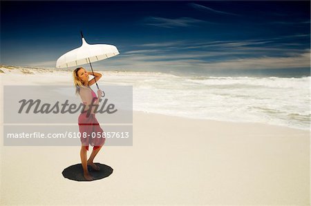 Young woman in bikini and pareo with parasol on the beach