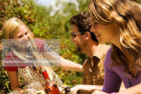 2 young women and a man sitting at garden table