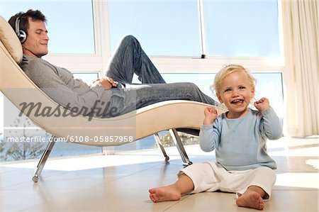 Father and little girl in living room, man listening to music, indoors