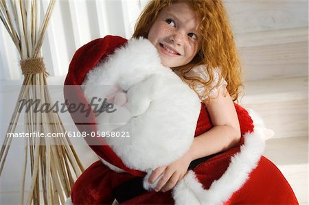 Christmas day, portrait of a little girl holding a cuddly toy (Santa Claus), indoors