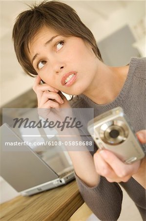 Young woman phoning, holding digital camera