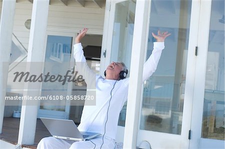 Man listening to music with laptop, arms in the air