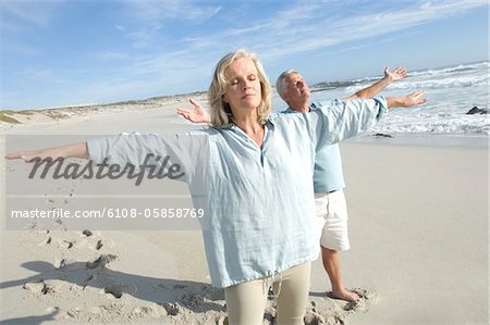 Couple with arms out on the beach, eyes closed