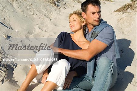 Couple embracing, sitting on the beach