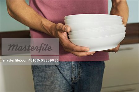 Young man carrying stack of plates