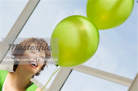 Portrait of young smiling woman holding green balloons