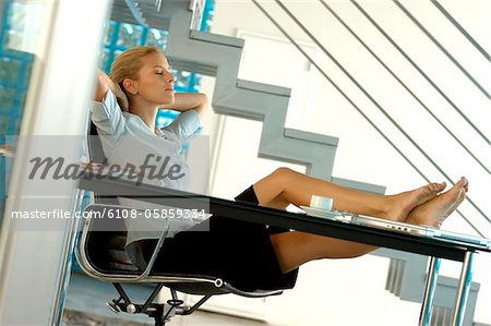 Young businesswoman resting in office with legs on desk