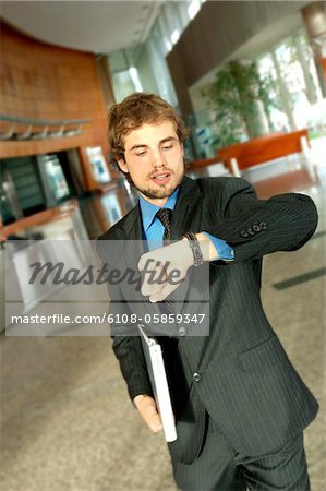 Young businessman looking at wristwatch