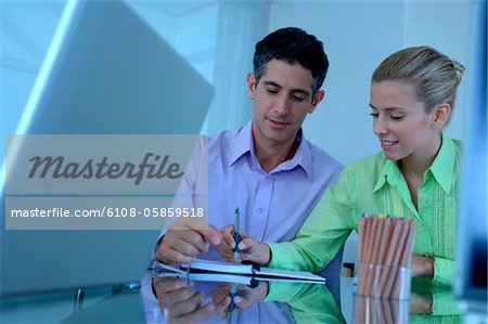 Businessman and businesswoman working in office, smiling