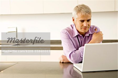 Mature man using a laptop in the kitchen