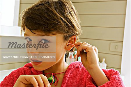 Portrait of a boy cleaning his ear with a cotton swab