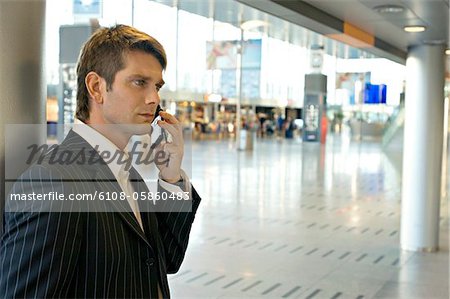 Side profile of a businessman talking on a mobile phone at an airport