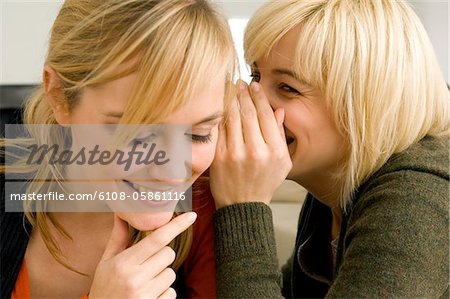 Close-up of a young woman whispering to her friend