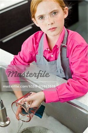 Portrait of a girl washing a measuring jug at a sink