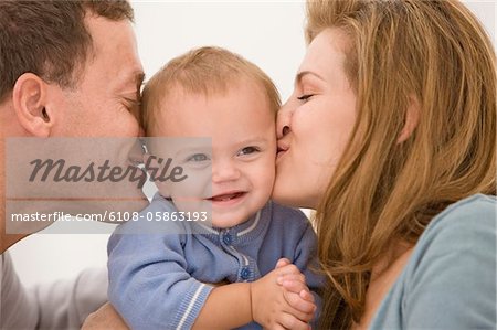 Parents kissing their daughter