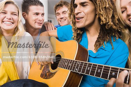 Man sitting with his friends and playing a guitar