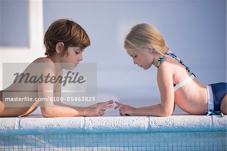 Boy with a girl playing at the poolside