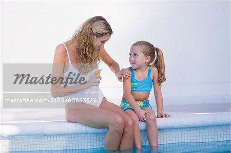 Woman with her daughter sitting at the poolside