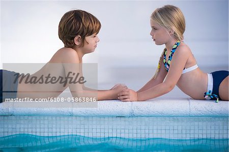 Boy with a girl lying at the poolside