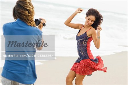 Man making a video of a dancing woman on the beach