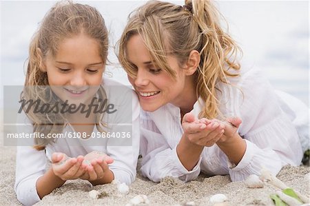 Woman lying with her daughter on the beach