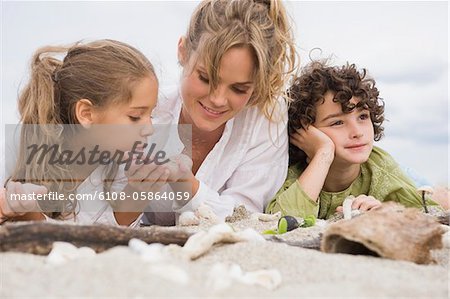 Woman lying with her children on the beach