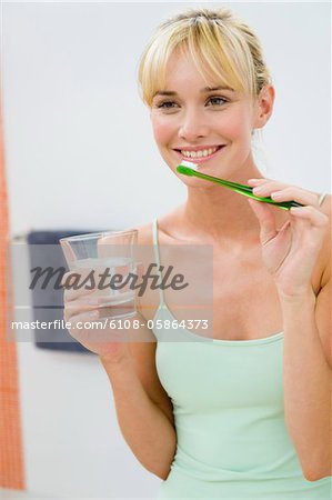 Woman holding a toothbrush with a glass of water