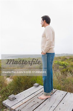 Man standing on a boardwalk and thinking