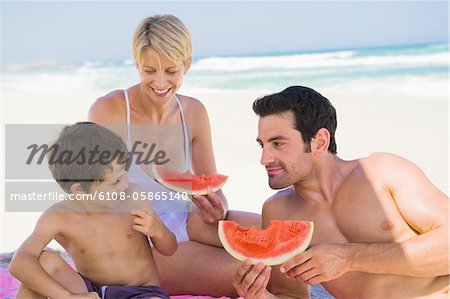 Family enjoying watermelon on the beach