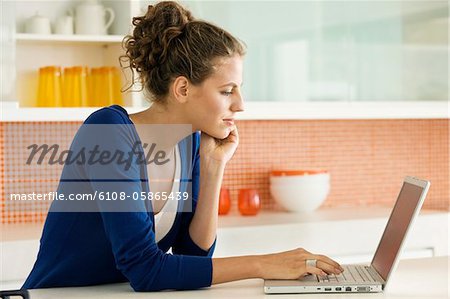 Woman reading a recipe on a laptop in the kitchen