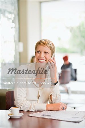 Businesswoman sitting in a restaurant and talking on a mobile phone