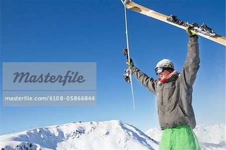 Young man holding his skis above his head