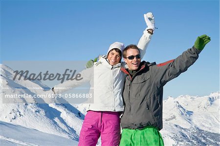 Young couple in ski wear, smiling at camera