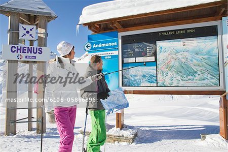 Couple of skiers looking at map, Courchevel, France