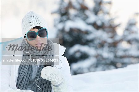 Young woman listening to MP3 player in snow