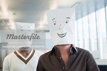 Two businessmen wearing paper bags of happy and sad faces Two businessmen wearing paper bags of happy and sad faces